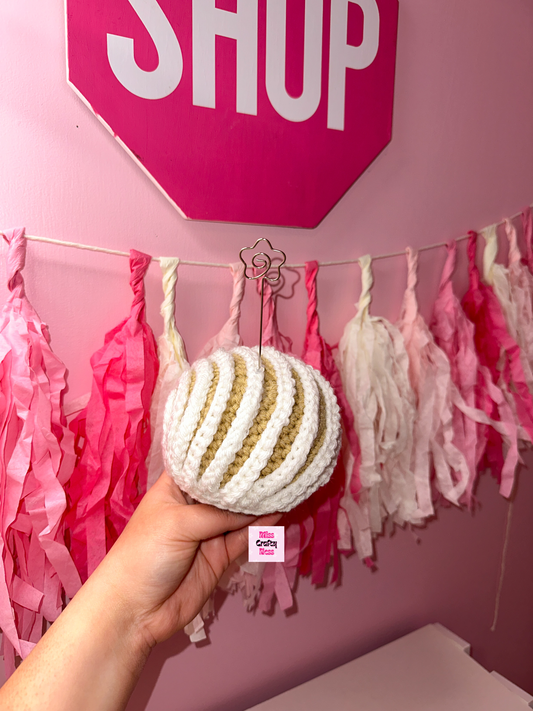 Crochet sweet bread photo holder item with pink and white tassels in the background.