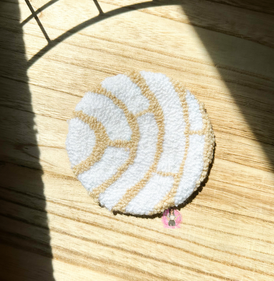 A white round sweet bread coaster on top of a wooden like surface.