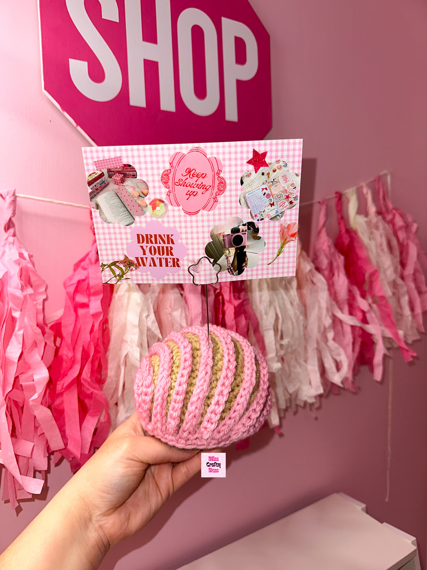 Crochet sweet bread photo holder item with pink and white tassels in the background.