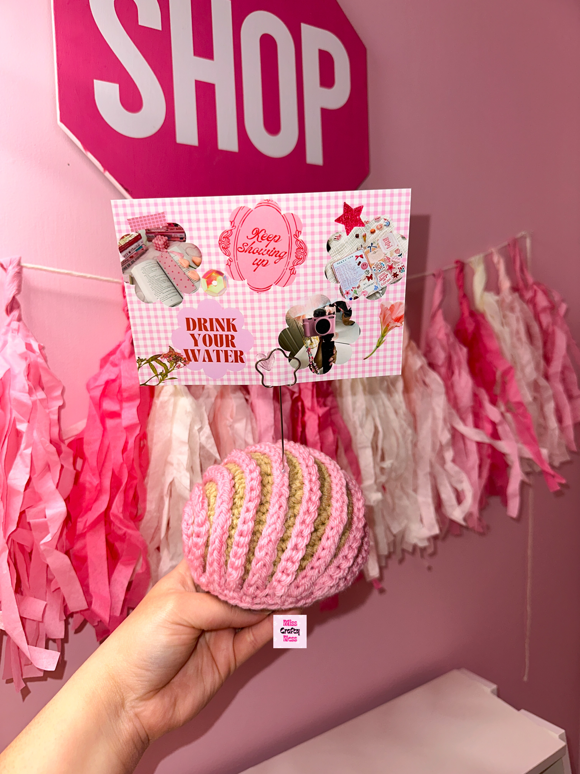 Crochet sweet bread photo holder item with pink and white tassels in the background.