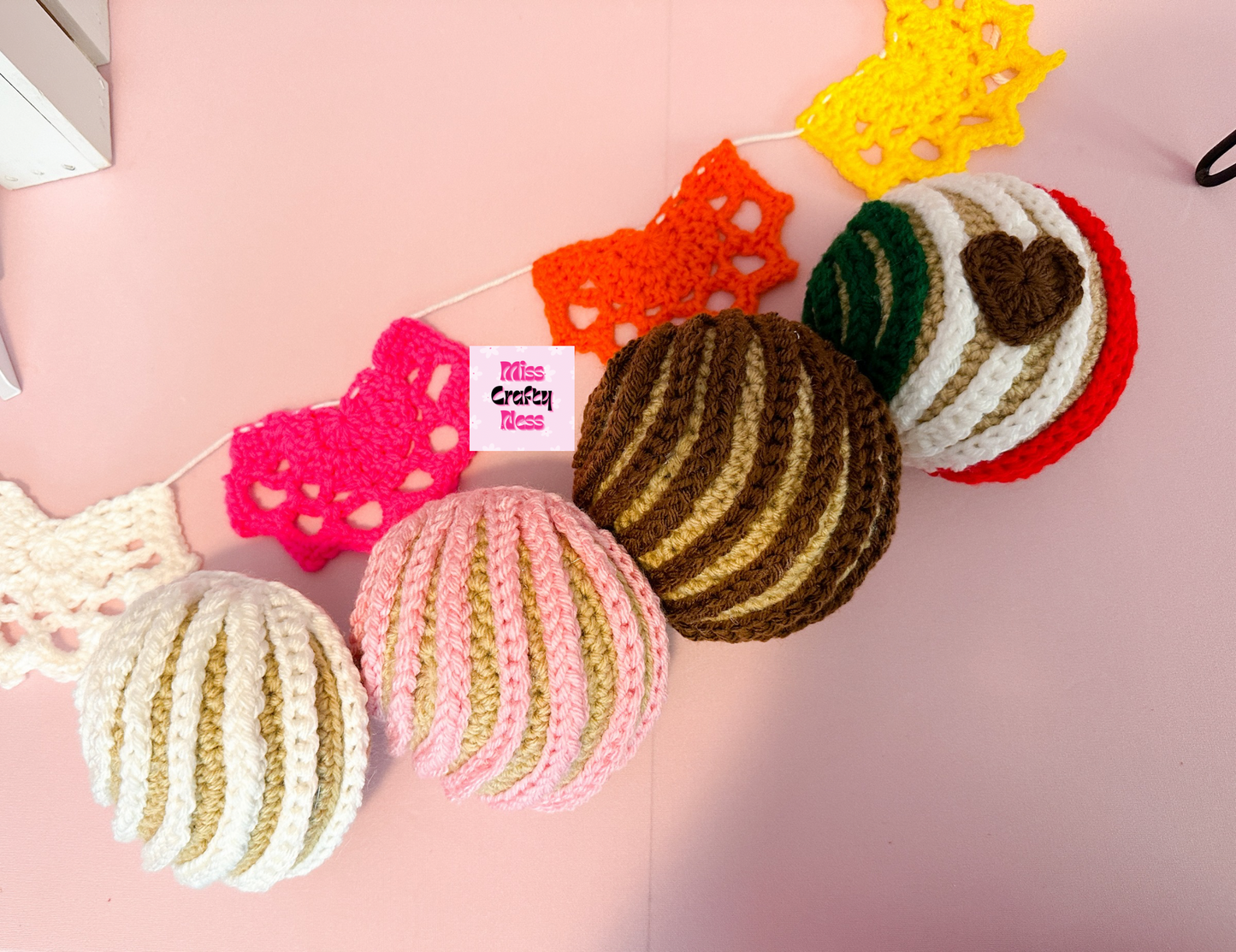 Colorful crocheted sweet bread and a crocheted doily pattern on a pink background